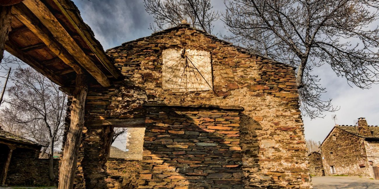 Stone building in an abandoned village with bare trees and rustic architecture.