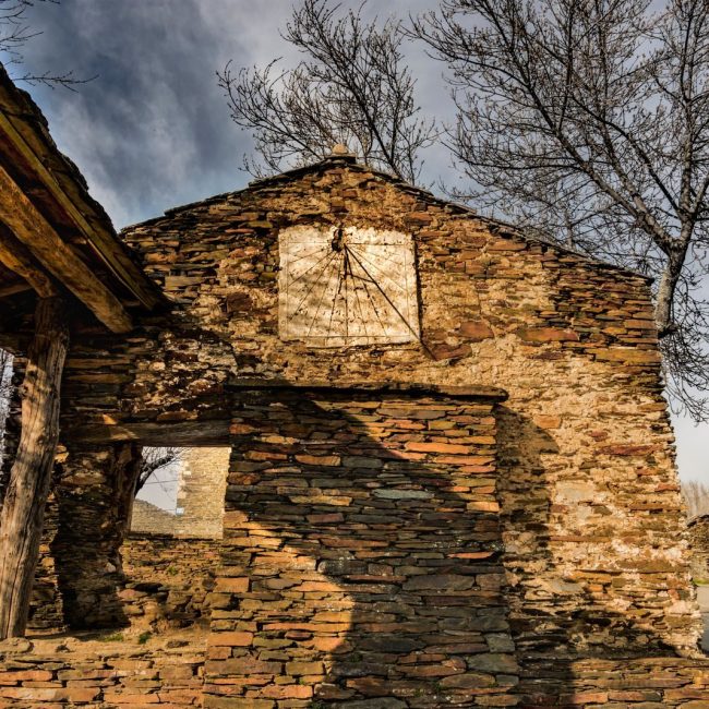 Stone building in an abandoned village with bare trees and rustic architecture.