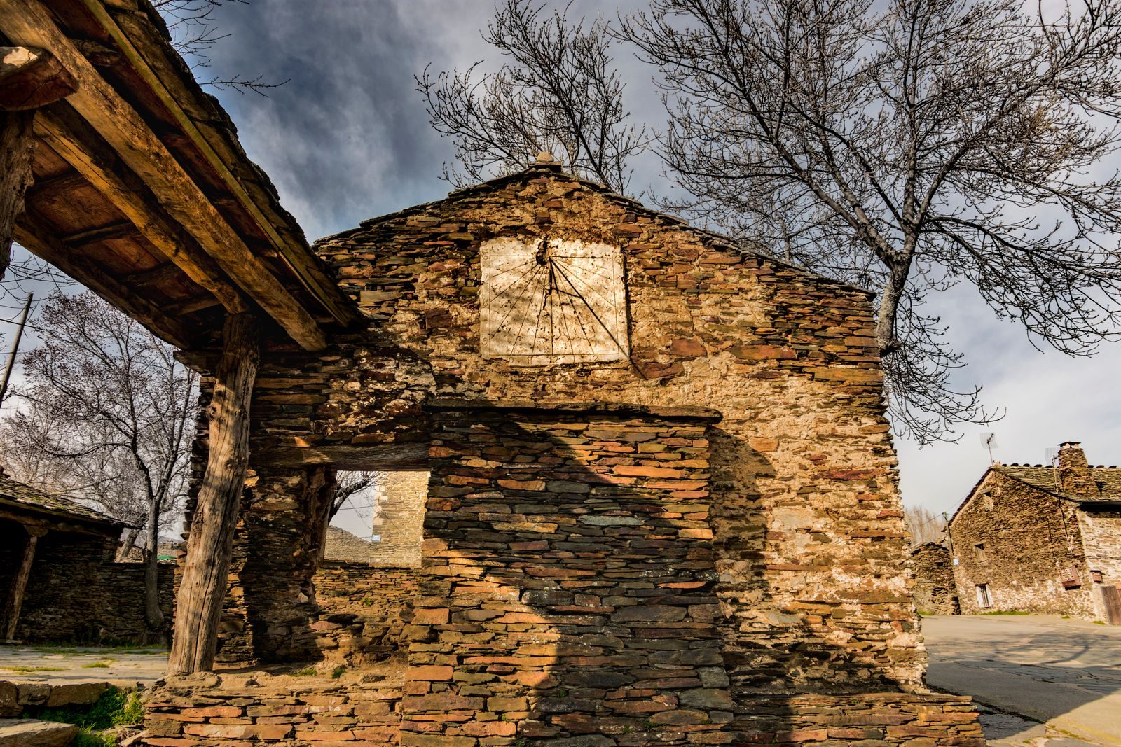 Stone building in an abandoned village with bare trees and rustic architecture.