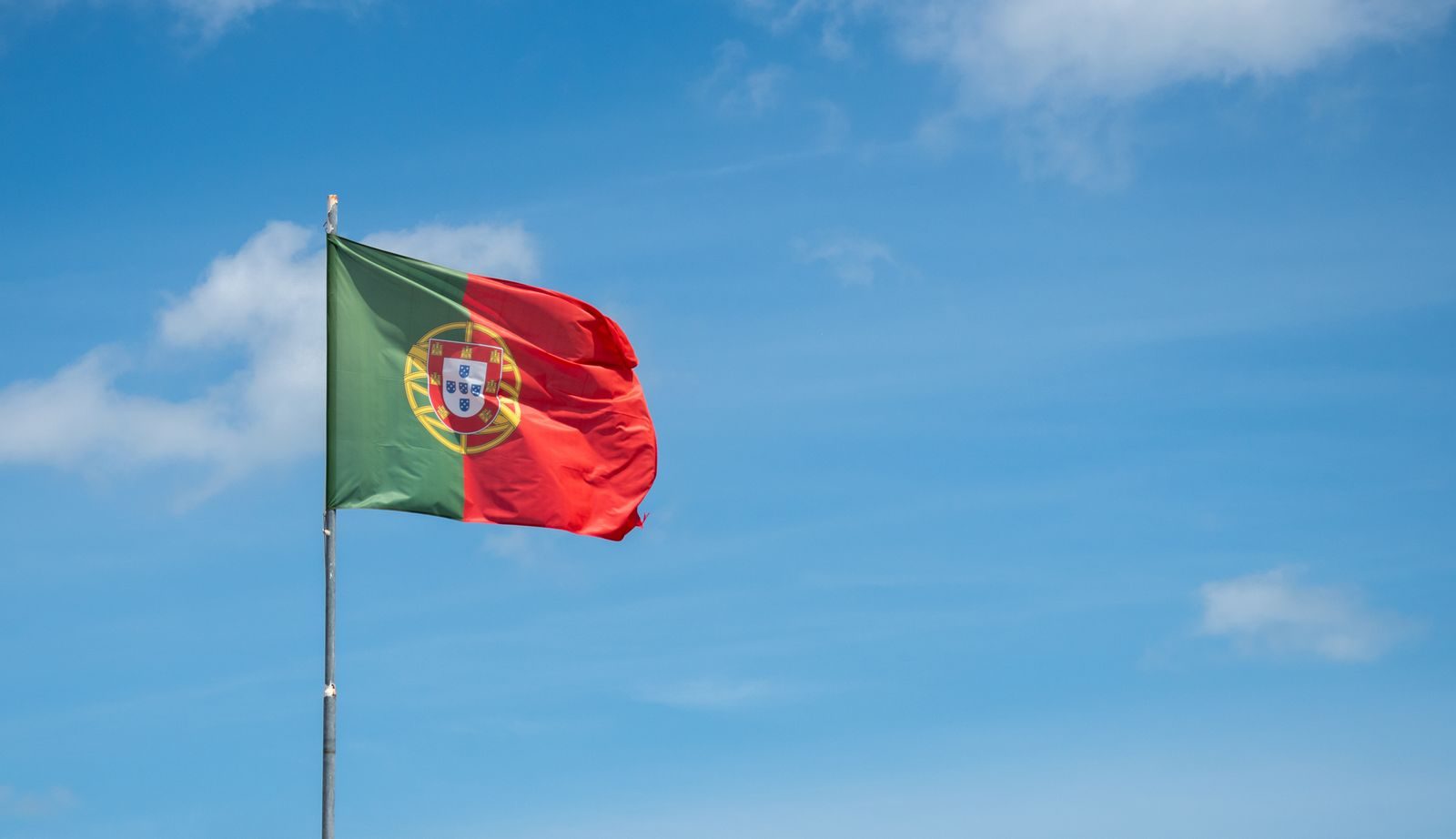 Vibrant Portuguese national flag gracefully waving against a clear blue sky in Cascais, Portugal.
