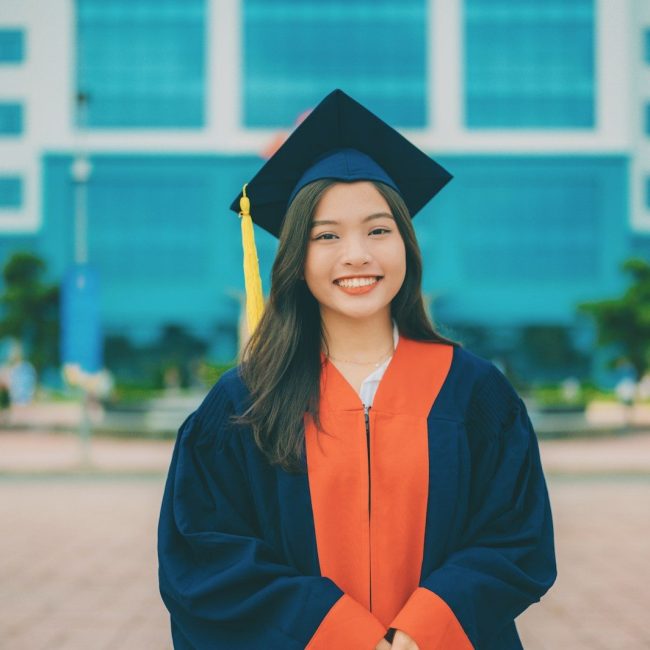 a woman in a graduation gown standing in front of a building